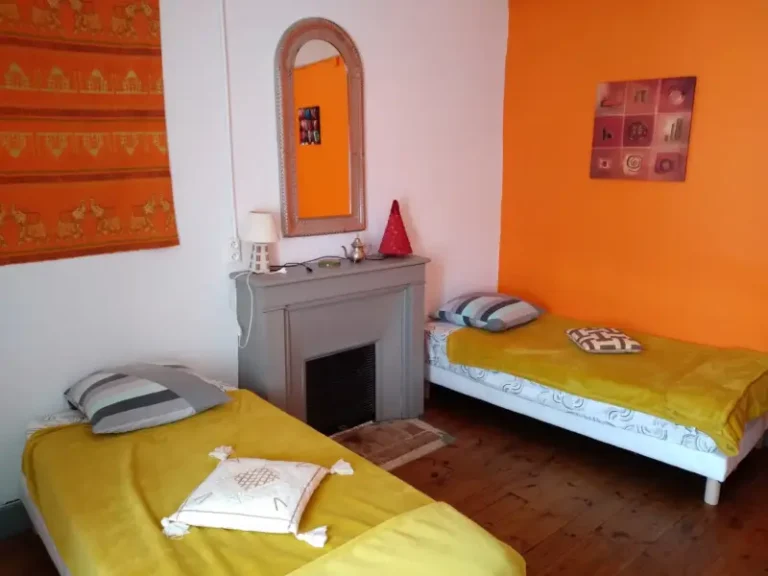 Chambre avec deux lits simples et mur orange