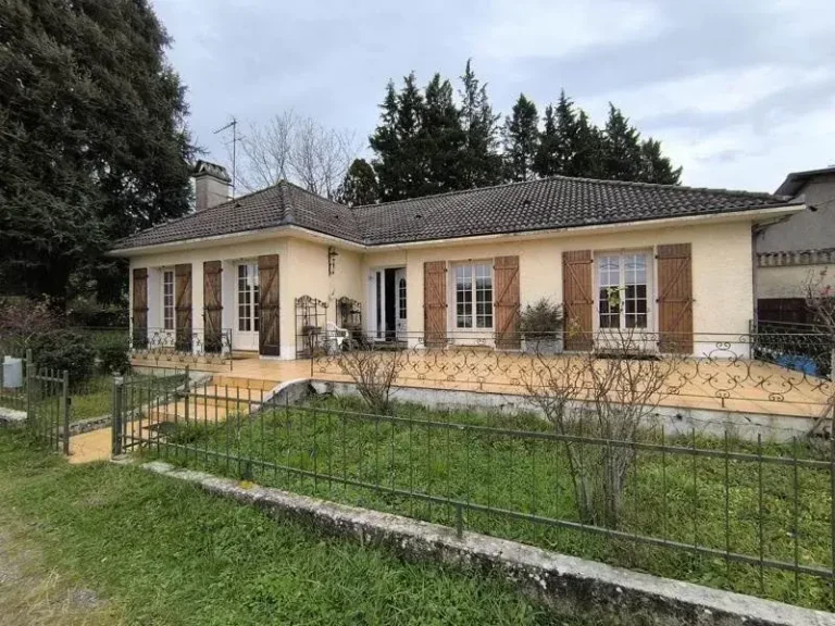 Maison avec jardin et fenêtres à volets.