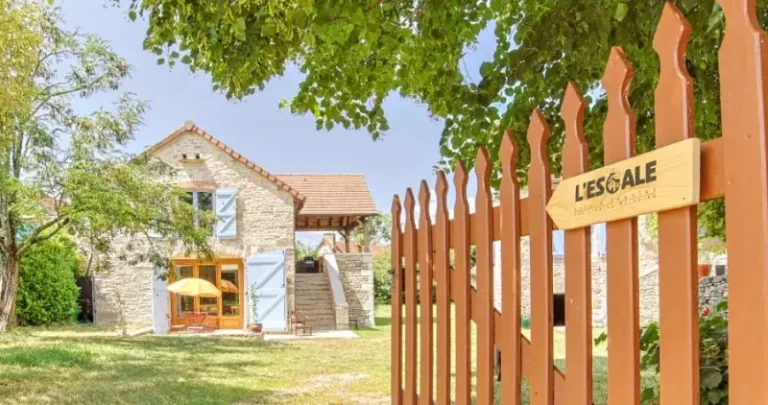 Maison en pierre avec jardin et clôture en bois.