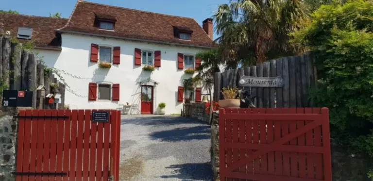 Maison blanche aux volets rouges avec portail ouvert