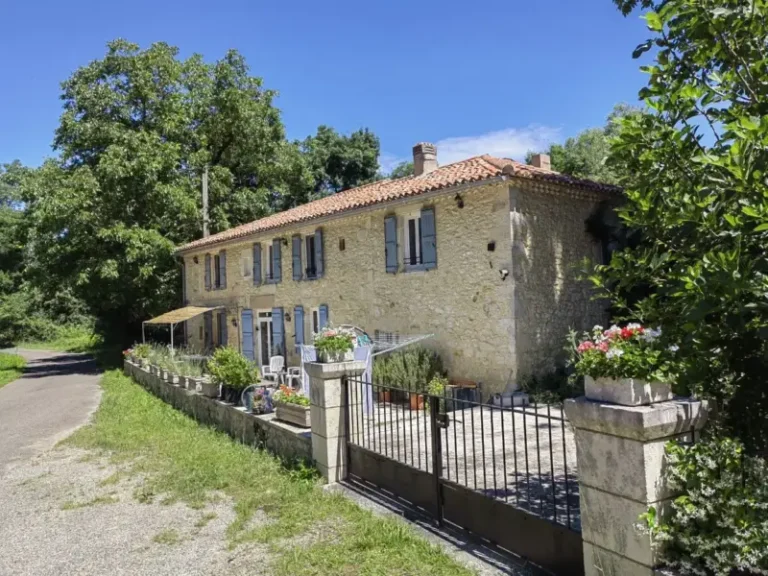 Maison en pierre avec volets bleus et jardin