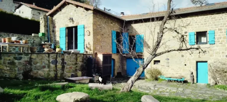 Maison en pierre avec volets bleus et jardin