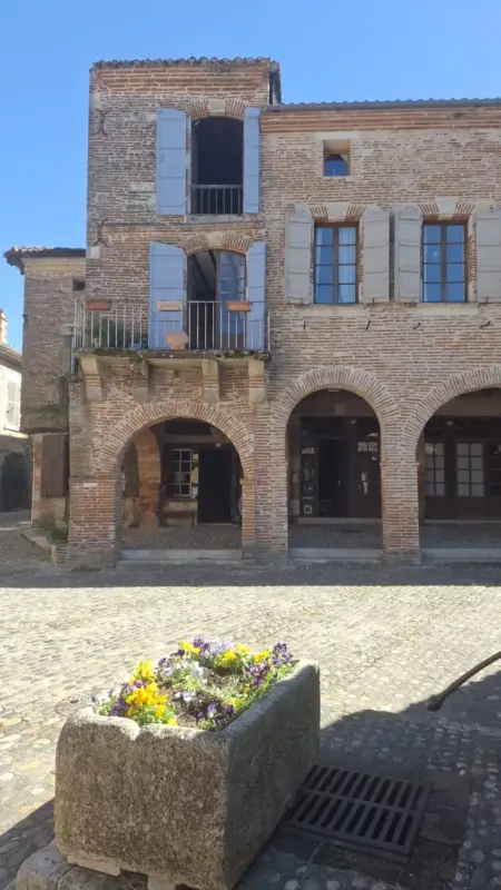 Bâtiment en briques avec arches et volets bleus