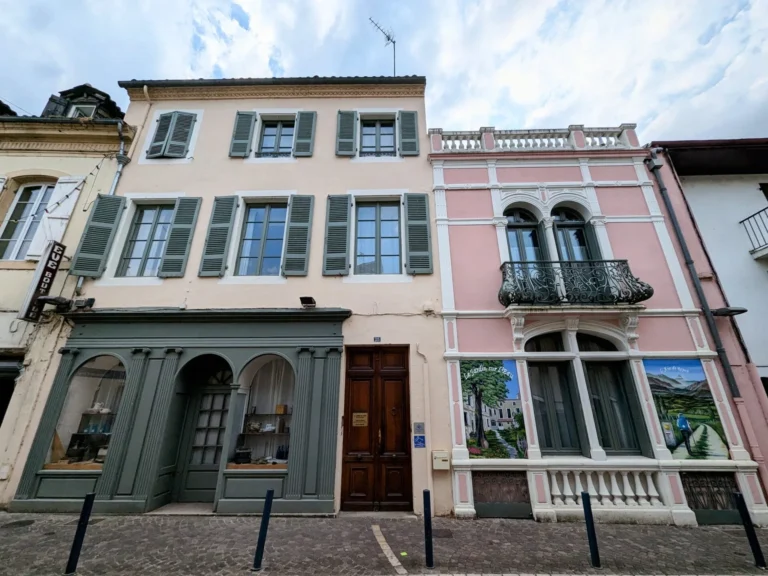 Façades pastel avec volets et balcon en fer