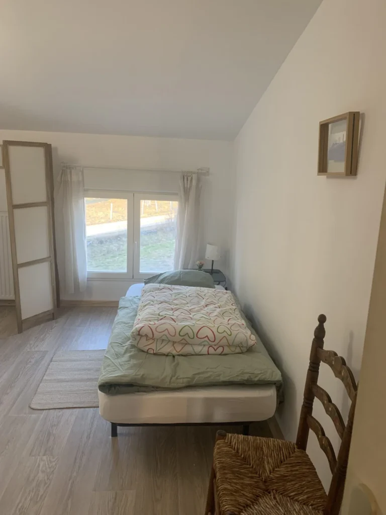 Petite chambre lumineuse avec lit simple et fenêtre