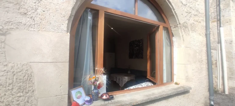 Fenêtre cintrée ouverte sur intérieur cosy en pierre